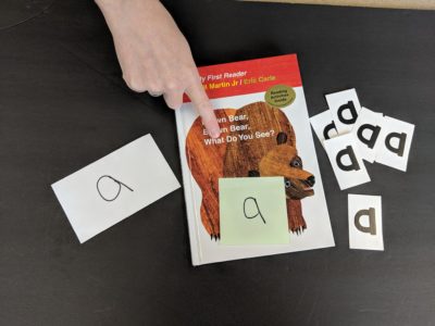 Cover of Brown Bear with hand pointing at a sticky note that has the letter 'a'